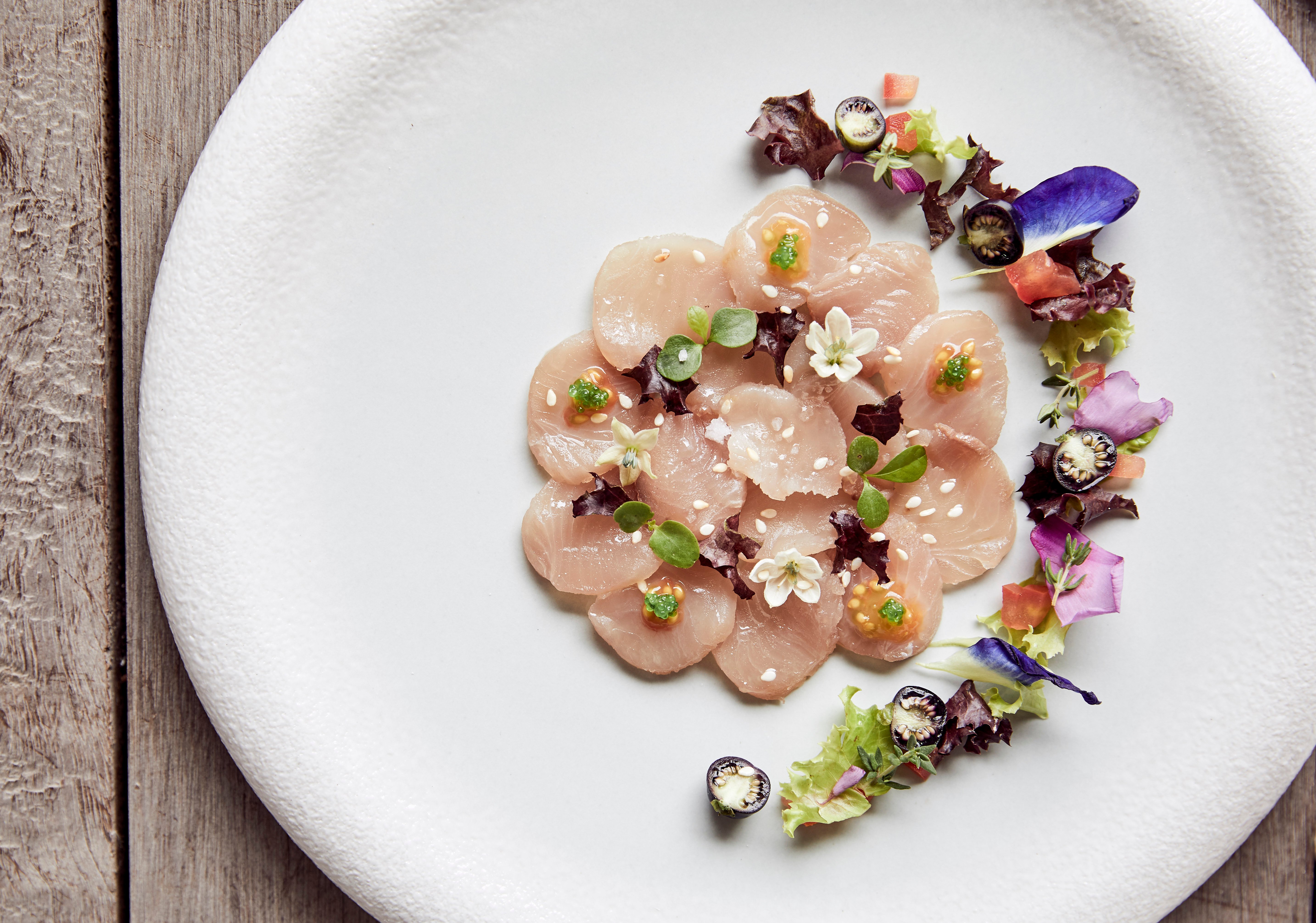 white_fish_carpaccio_with_edible_flowers_in_white_plate_treetops