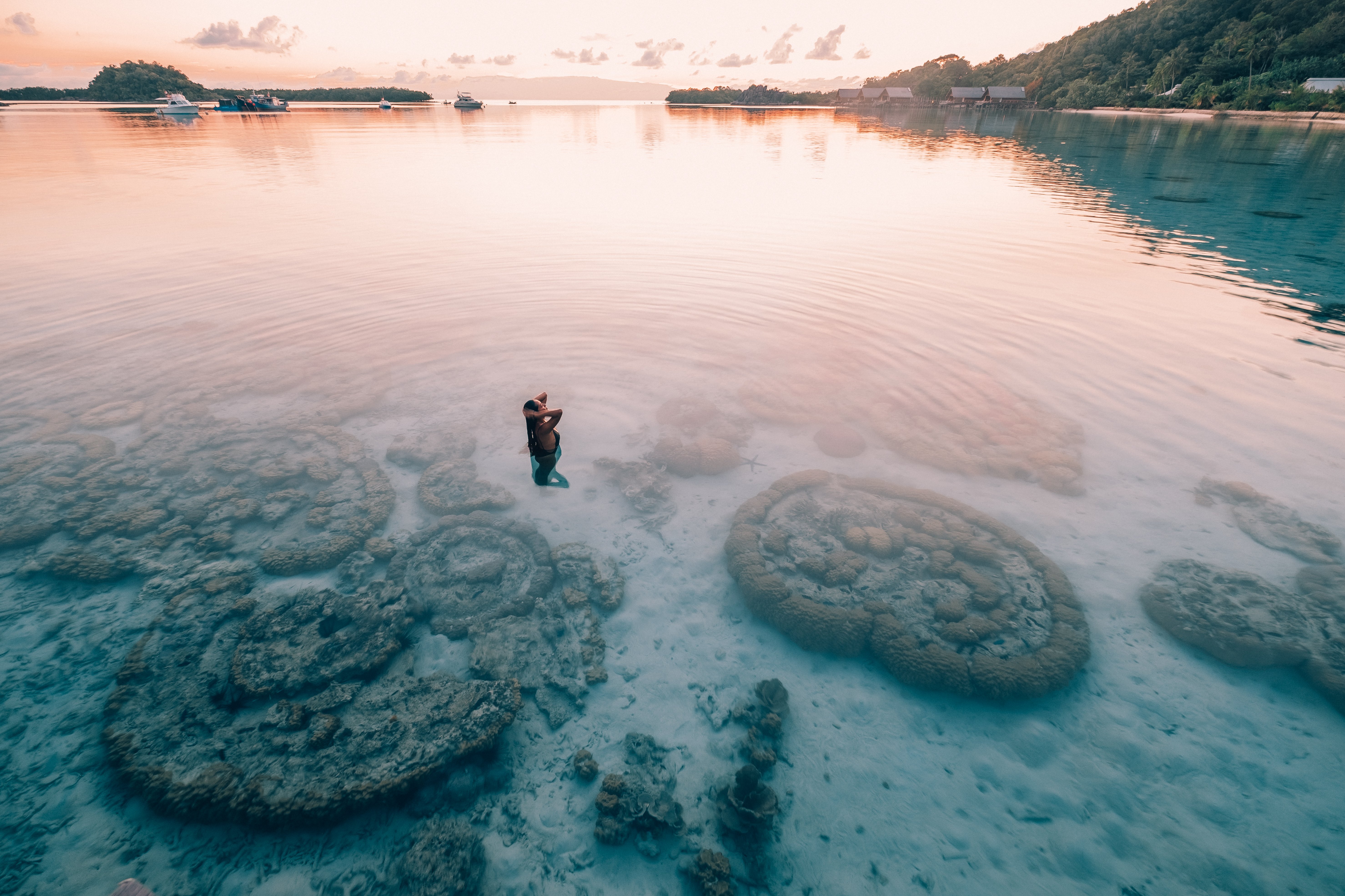asian_woman_soak_in_coral_reefs_lagoon_hand_on_hair_with_west_overwater_view_at_sunset