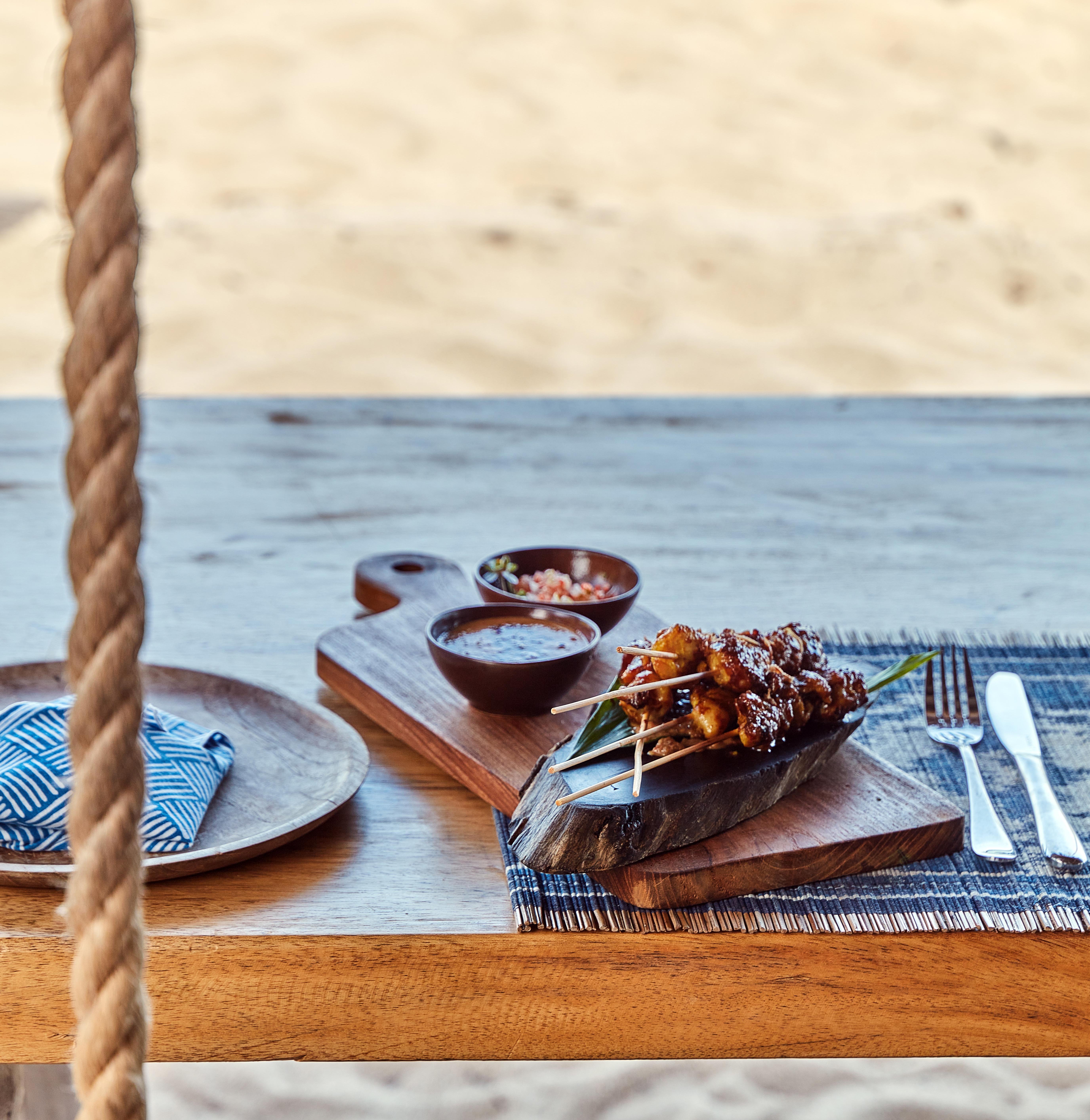 grilled_satay_with_peanut_sauce_served_on_wooden_serving_board_rope_swing_table_boat_house (1) (1)