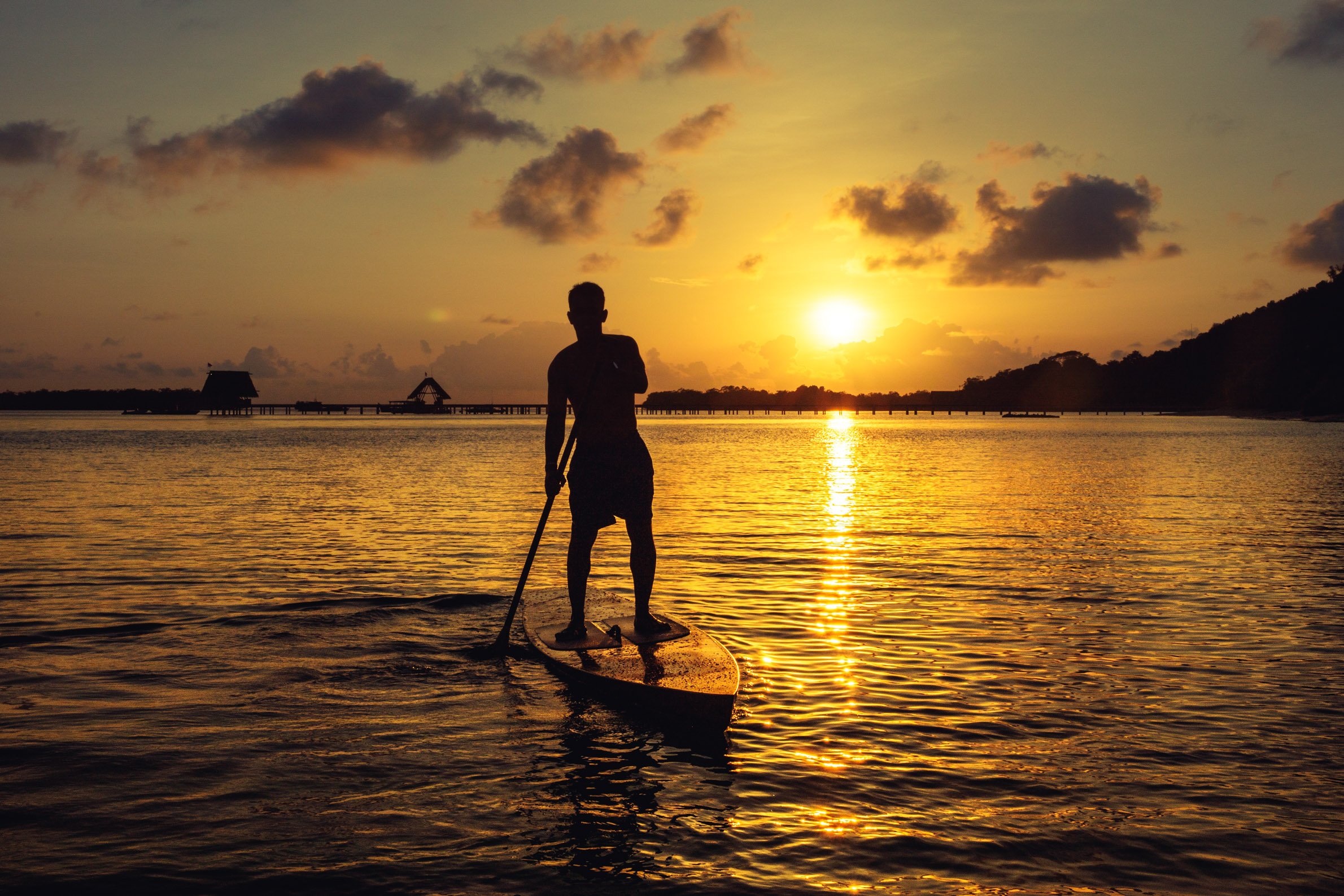 silhouette_man_shirts_off_stand_up_paddle_board_looking_sunset_jetty_lagoon