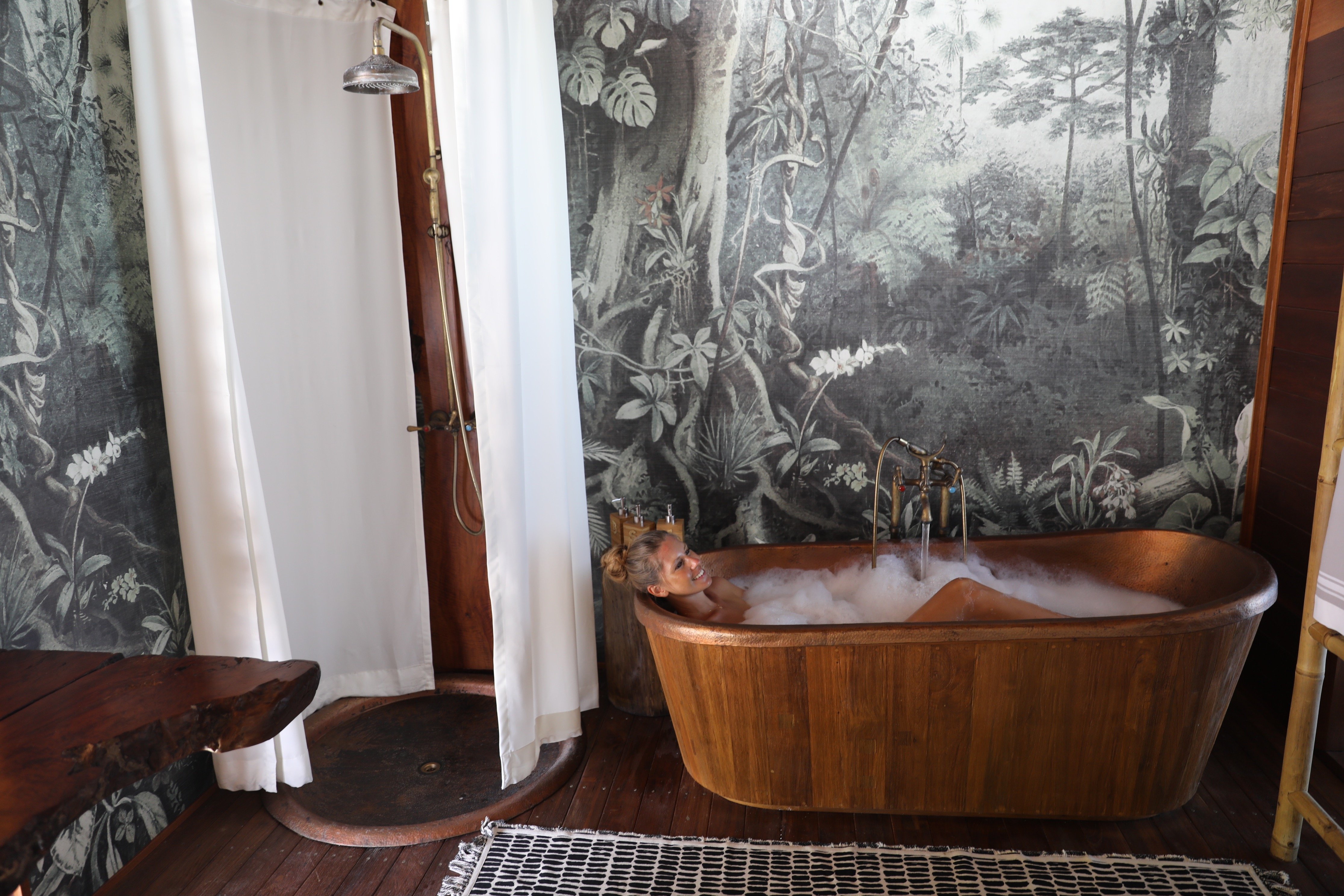 white_woman_relaxing_in_bubble_copper_bath_tub_overwater_suite