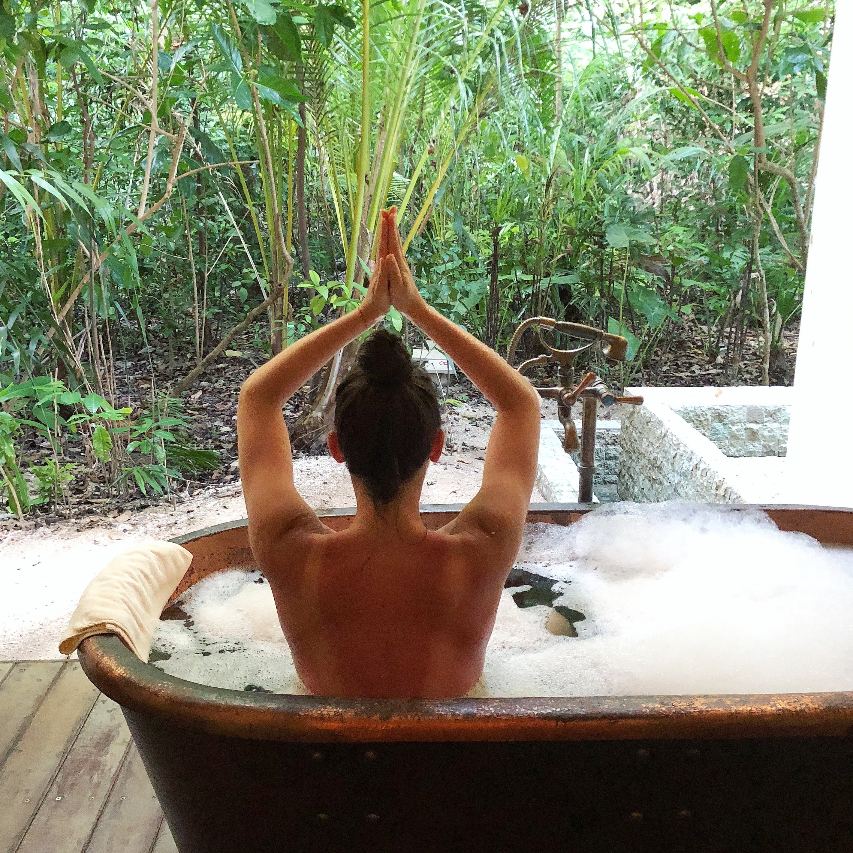 young_woman_practicing_yoga_pose_lotus_pose_with_raised_prayer_hands_in_copper_bubble_bath_tub_aura_spa